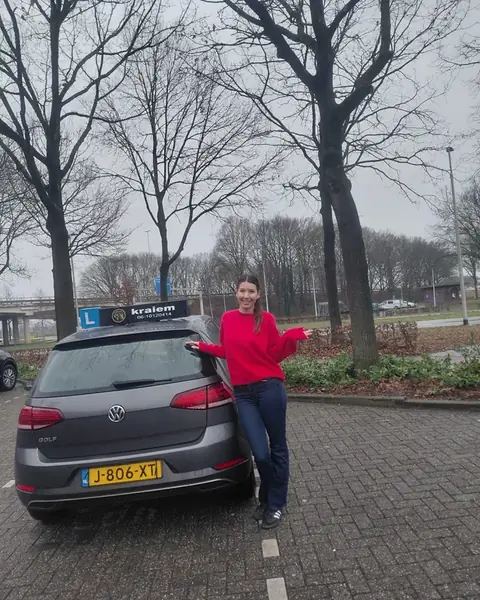 Leerling geslaagd voor haar rijbewijs naast de lesauto van Rijschool Kraiem