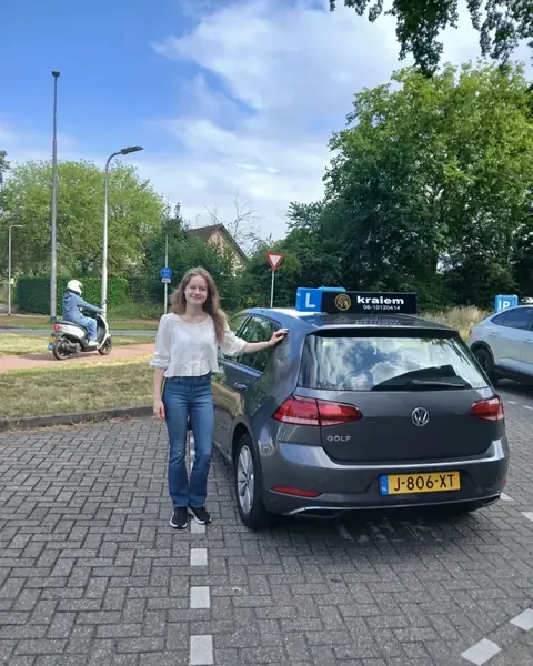 Leerling geslaagd voor het praktijkexamen naast de lesauto van Rijschool Kraiem in Tilburg